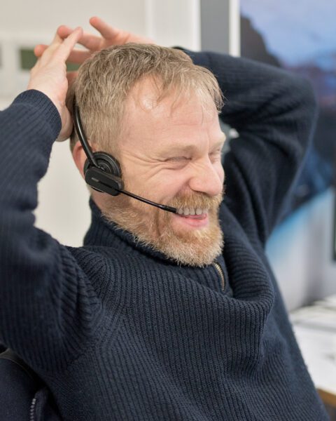 Chris smiles whilst engaging over the phone.