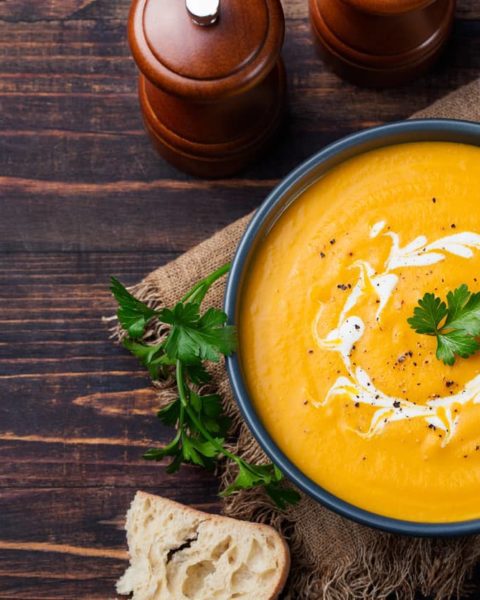 Well presented bowl of soup on darkwood table.