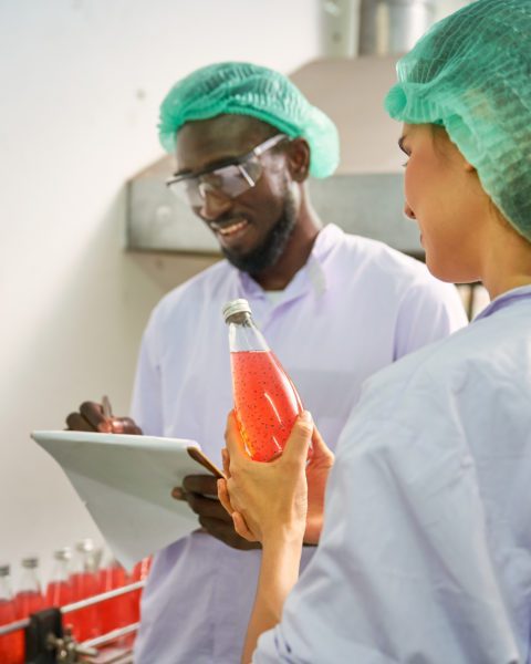 two people in hair nets holding produce and a clipboard